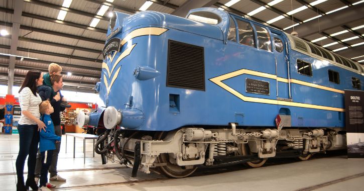 A young family looking at an old train