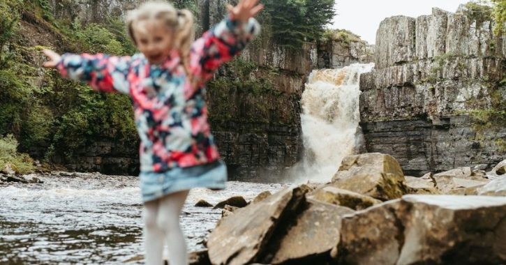 A young girl having fun near High Force Waterfall