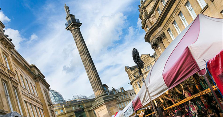 View of Grey's Monument in Newcastle-upon-Tyne surrounded by buildings and market stalls