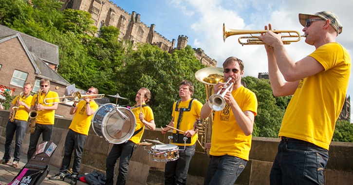 brass band playing music on Framwellgate Bridge with Durham Castle in background. 