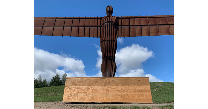 Replica of St Cuthbert’s coffin showing carvings of angels in front of The Angel of the North