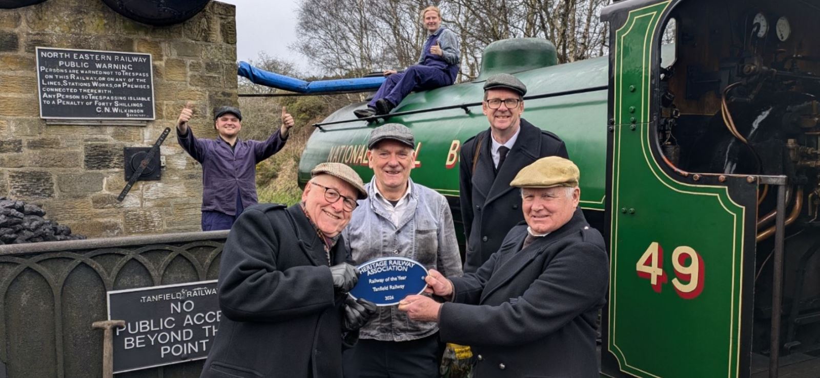 A group of people holding an award in front of a train