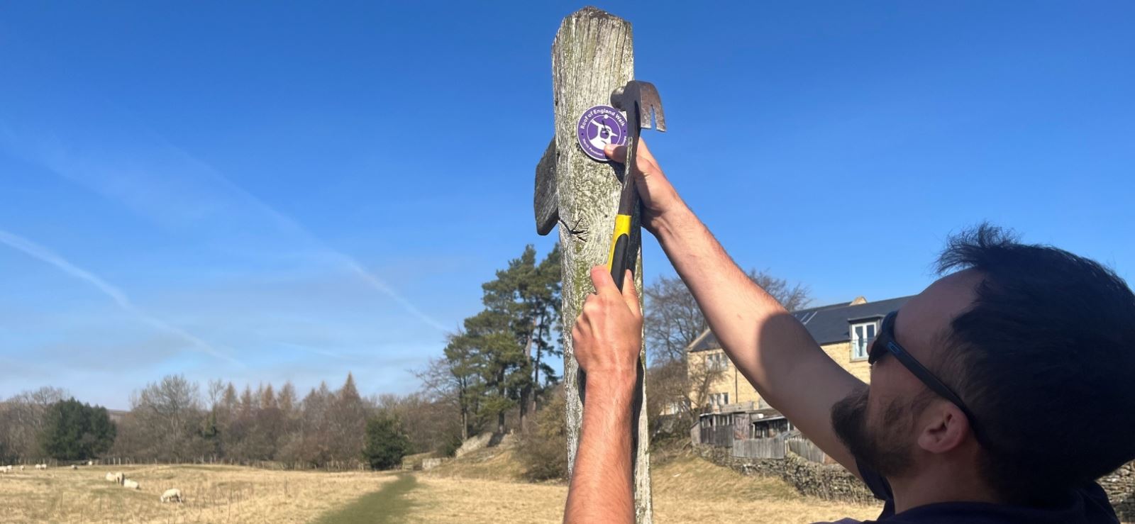 A man putting a way finder on a post