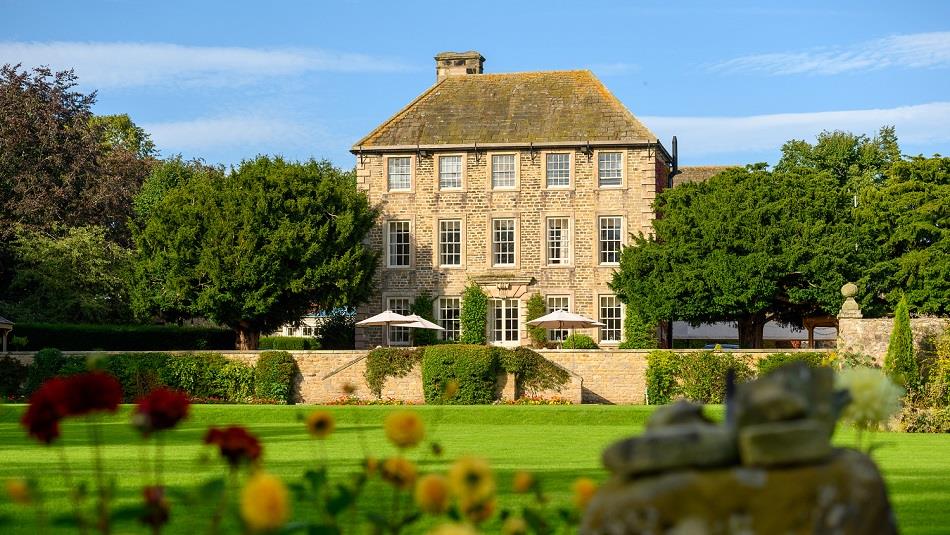 Exterior view of Headlam Hall, blue skies with gardens in foreground.