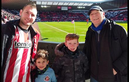 Two men and two young boys in the stadium of light