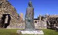 Statue of St. Cuthbert at Lindisfarne Priory on a sunny day - English Heritage.