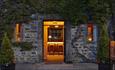 View of a bar taken from outside, looking through the doorway. Potted plants either side of the doorway and ivy climbing the walls.