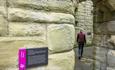 Image of a visitor walking through an archway into the Great Hall at Warkworth Castle - English Heritage.