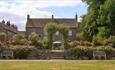 View of the main house at Lord Crewe Arms surrounded by flowers in the garden on a bright sunny day.