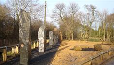 Image by Jack Turton. Stone monoliths decorated with mining paraphernalia.