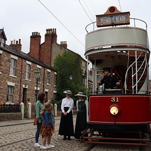 Image of the 1900s Town Street at Beamish Museum, people waiting to board the tram. 