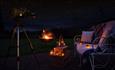 A cosy outdoor seating area under the stars with a firepit and candles.