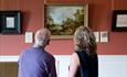 Two people looking at artwork inside Auckland Castle
