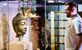 man looking at display with large golden Buddha head